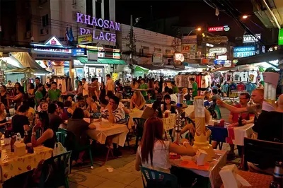 a crowd of people sitting at tables in a street at night at xxzNAP - Khaosan Road สแนป ตรอกข้าวสาร in Bang Bua Thong Railway Station