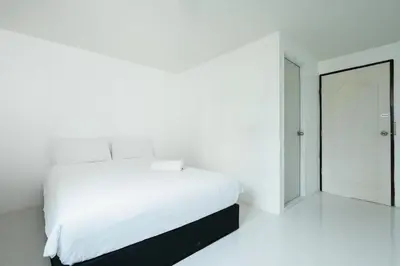 a white bedroom with a white bed and a mirror at SleepPop Sukhumvit 42 - BTS Ekkamai in Phra Khanong