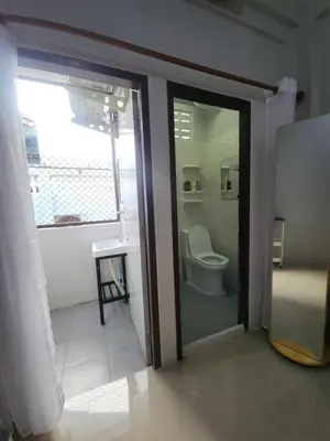 a bathroom with a toilet and a glass door at Sabai room in Taling Chan
