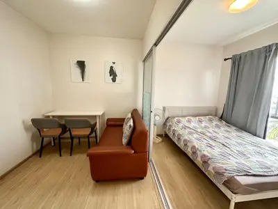 a bedroom with a bed and a chair and a table at Plum condo Bang-yai station in Nonthaburi