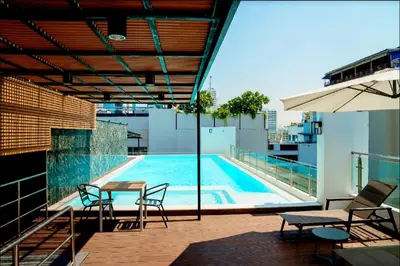 a pool on the roof of a building with chairs and an umbrella at 6th Avenue Sukhumvit BKK 409 BTS Asoke Nana MRT Sukhumvit in Bangkok