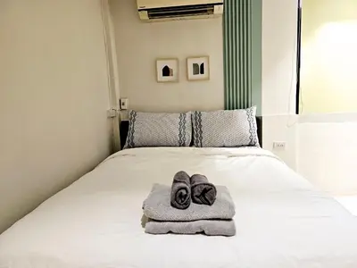 a bed with a towel and pair of shoes on it at W House in Phra Khanong