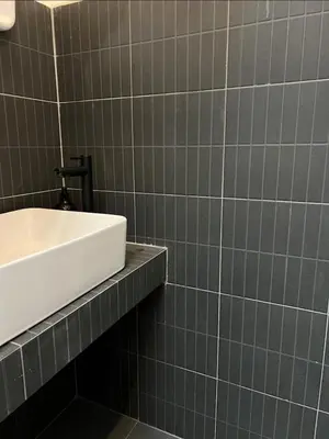 a bathroom with a sink and a tiled wall at Bongo Residence Ratchathewi Bangkok in Bangkok