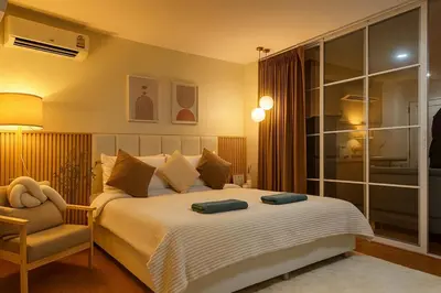 a bedroom with a large bed and a chair at Cozy Designer Apartment - Sukhumvit 39 in Bangkok