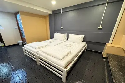 a bed with white sheets and pillows in a room at Pratunam Family House in Ban Nong Chaeng
