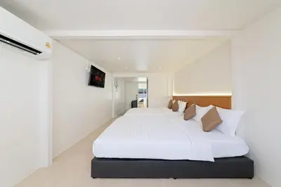 a white bedroom with a large white bed with pillows at OH Suites 72 in Bangkok