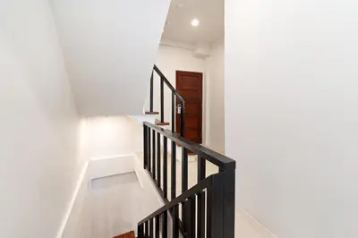 a staircase in a house with white walls and black railings at OH Suites 72 in Bangkok