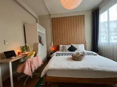 a bedroom with a bed with a desk and a window at Office 3 in Bangkok