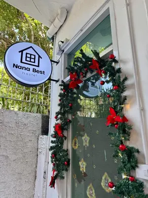 a window with christmas wreaths and a sign on it at Nana Best Hostel in Makkasan