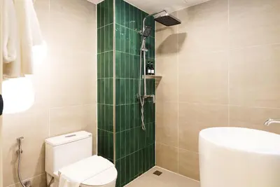 a bathroom with a toilet and a green shower at Palma Hotel in Bangkok