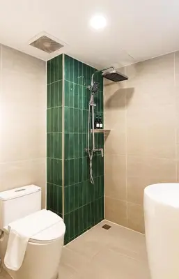 a green tiled bathroom with a toilet and a shower at Palma Hotel in Bangkok
