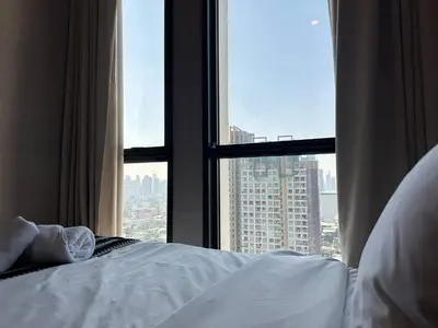 a bed in front of a window with a city view at 072-Cap-A-R266-F24 in Ban Na Song