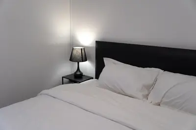 a white bed with a black headboard and a lamp at The Lodge Bangkok Poolvilla 2 in Sathani Khlong Tan