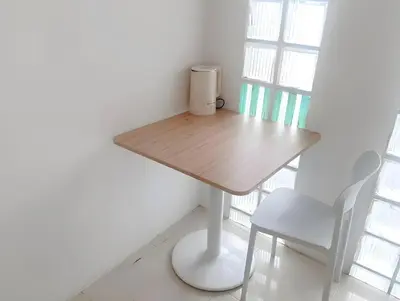 a wooden table and chair in a room with a window at XX Mitr INN Sukhumvit Soi 2 in Bang Kapi