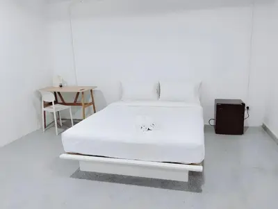 a white bed in a white room with a table at XX Mitr INN Sukhumvit Soi 2 in Bang Kapi