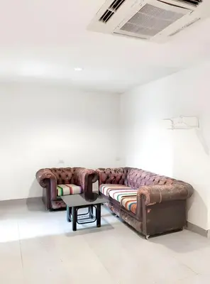 a brown couch in a white room with a table at XX Mitr INN Sukhumvit Soi 2 in Bang Kapi