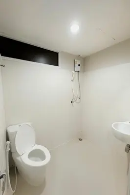 a white bathroom with a toilet and a sink at Minimal condo 5 mins to mrt Suthisarn in Bangkok