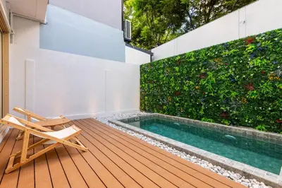 a deck with a pool and a chair and a plant at Spacious 4BR Muji Home with Loft Pool in Ekkamai in Bangkok