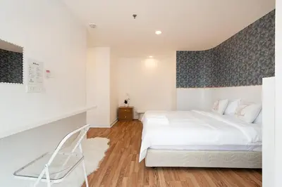 a bedroom with a white bed and a chair at Elegant King BR Apt Bathtub, BTS Central BKK BTB8 in Bangkok