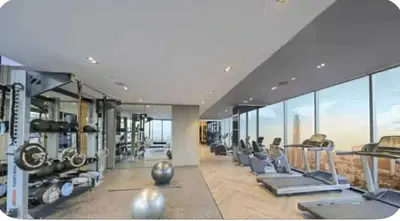 a gym with cardio equipment in a building with windows at Park payathai 28 in Bangkok