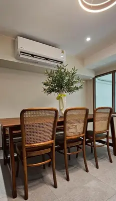a dining room with a table with chairs and a plant at Loly Residence in Bangkok
