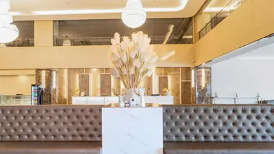a restaurant with a leather bench and a vase of flowers at Enrich Grand Hotel in Bangkok