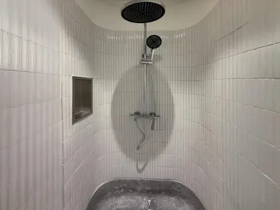 a shower with a tub in a white tiled bathroom at Brown H in Pom Prap