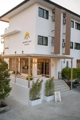 a white building with potted plants in front of it at Morning Place in Ban Krathum Lom