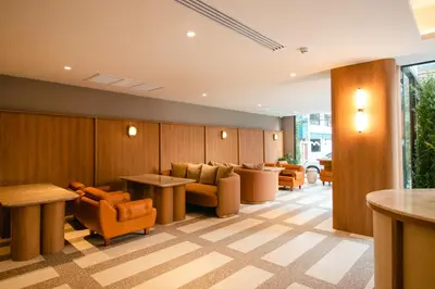 a waiting room with orange chairs and tables at Marwin Terra Hotel in Bangkok