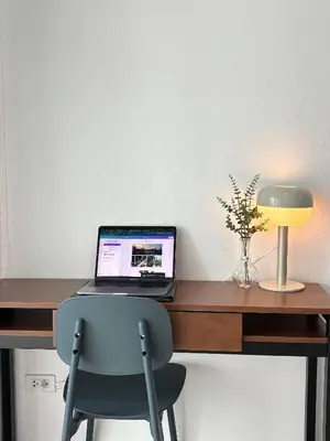 a laptop computer sitting on a wooden desk with a chair at 1minBTS-Wifi500Mbs-Workplace>NETFLIX/Central in Khlong Toei