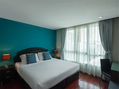 a bedroom with a white bed and a blue wall at Silom Lofts in Bangkok