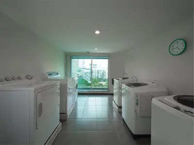 a kitchen with white appliances and a clock on the wall at Silom Lofts in Bangkok