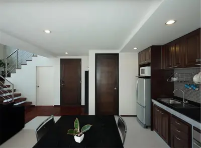 a kitchen with a dining table and a kitchen with a staircase at Silom Lofts in Bangkok