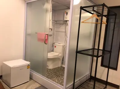 a small bathroom with a toilet and a glass door at Bluefin Guesthouse in Bangkok