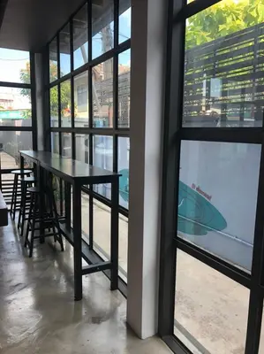 a table and chairs in a room with windows at Bluefin Guesthouse in Bangkok