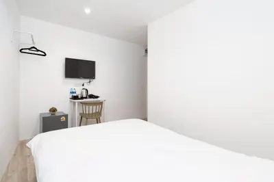a bedroom with a white bed and a desk at z Rest Inn Silom - เรสท์ อินน์ สีลม in Bang Rak
