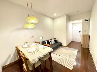 a dining room with a table and a couch at Common Living Bangkok in Bangkok