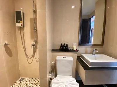a bathroom with a shower and a toilet and a sink at Yotaka Bangkok Hotel in Bangkok
