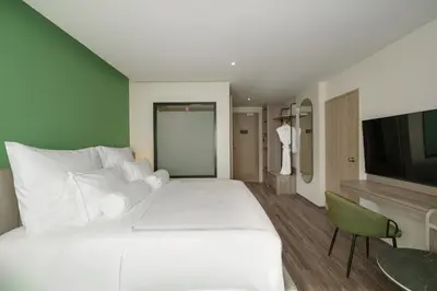 a hotel room with a large white bed and a tv at The Akyra Bangkok 11 in Bangkok