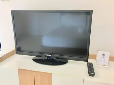 a computer monitor on a desk with a remote control at Grandview Ladprao Hotel in Bangkok