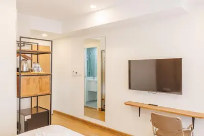 a room with a tv on a wall with a table and a chair at Believeinn in Bangkok