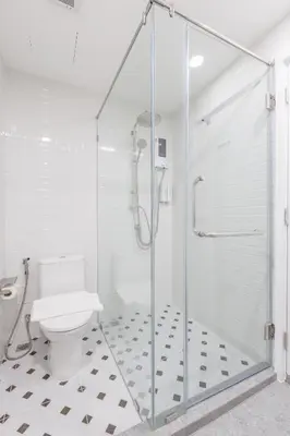 a white bathroom with a shower and a toilet at Believeinn in Bangkok