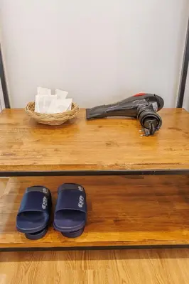 a black umbrella and two slippers on a wooden shelf at Believeinn in Bangkok