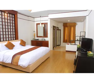 a bedroom with a bed and a desk and a television at Palette Bangkok Natural Resort and Spa in Bangkok