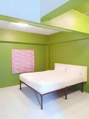 a bed in a room with a green wall at xx GO INN Grand Palace - โก อินน์ พระบรมมหาราชวัง เจริญกรุง 1 in Bangkok