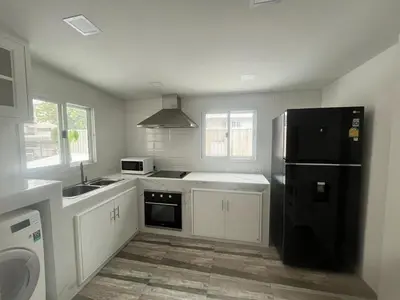 a kitchen with a black refrigerator and white cabinets at Huai Khwang Townhome in Ban Na Song
