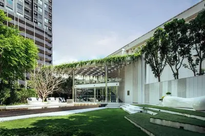 a large building with a green yard with benches at 2 Bed 2 Bath Condo Steps to BTS&MRT in Bangkok
