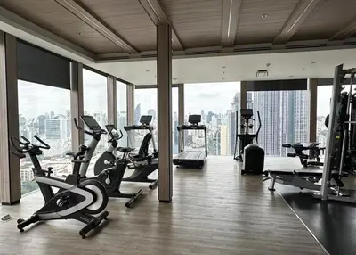 a gym with cardio equipment in a large room with windows at Thonglor Ekkamai 10 mins Sky Pool 1BR in Bangkok