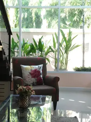 a living room with a chair and a glass table at Cozy and Convenient Bangna House in Ban Khlong Samrong