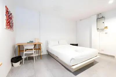 a white bedroom with a bed and a table at XX Mitr Inn Sukhumvit Soi 2 - มิตร อินน์ สุขุมวิท ซอย 2 BTS Nana in Bang Kapi